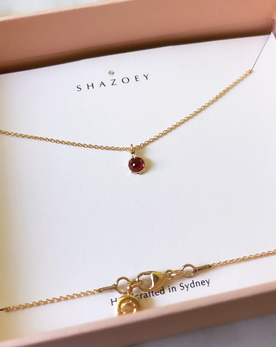 January birthstone necklace with a red garnet pendant on a fine gold chain