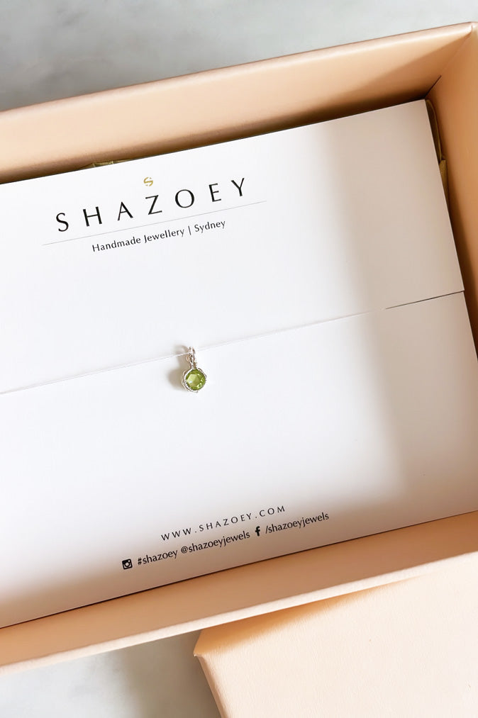 A sterling silver peridot pendant on a Shazoey branded card in gift box