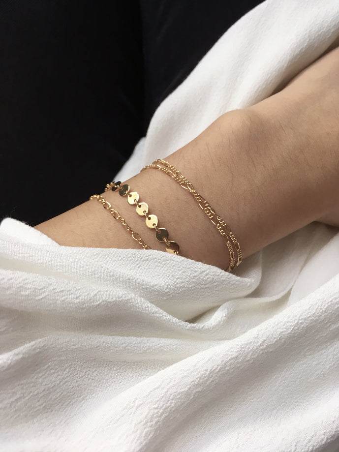 Dainty delicate gold chain bracelets stack worn by model - 14k gold filled figaro chain, gold disc chain and gold round link chain