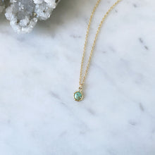 A gold Australian turquoise pendant on a fine gold cable chain on a marble table
