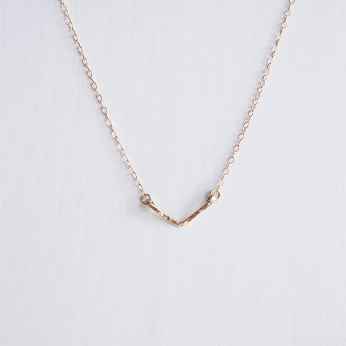 A minimalist rose gold hand hammered chevron necklace