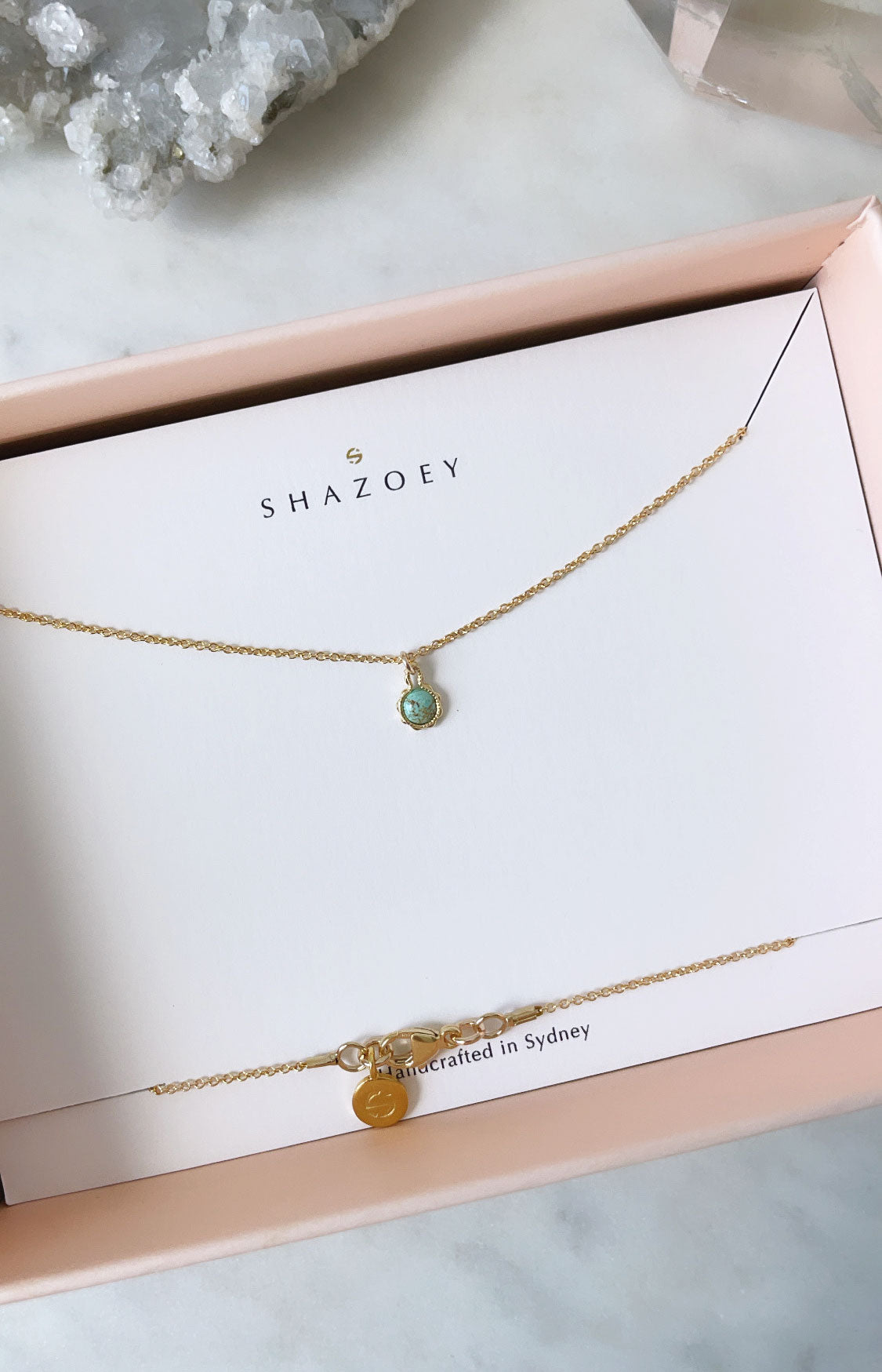 Gold birthstone necklace with turquoise pendant in a pink gift box