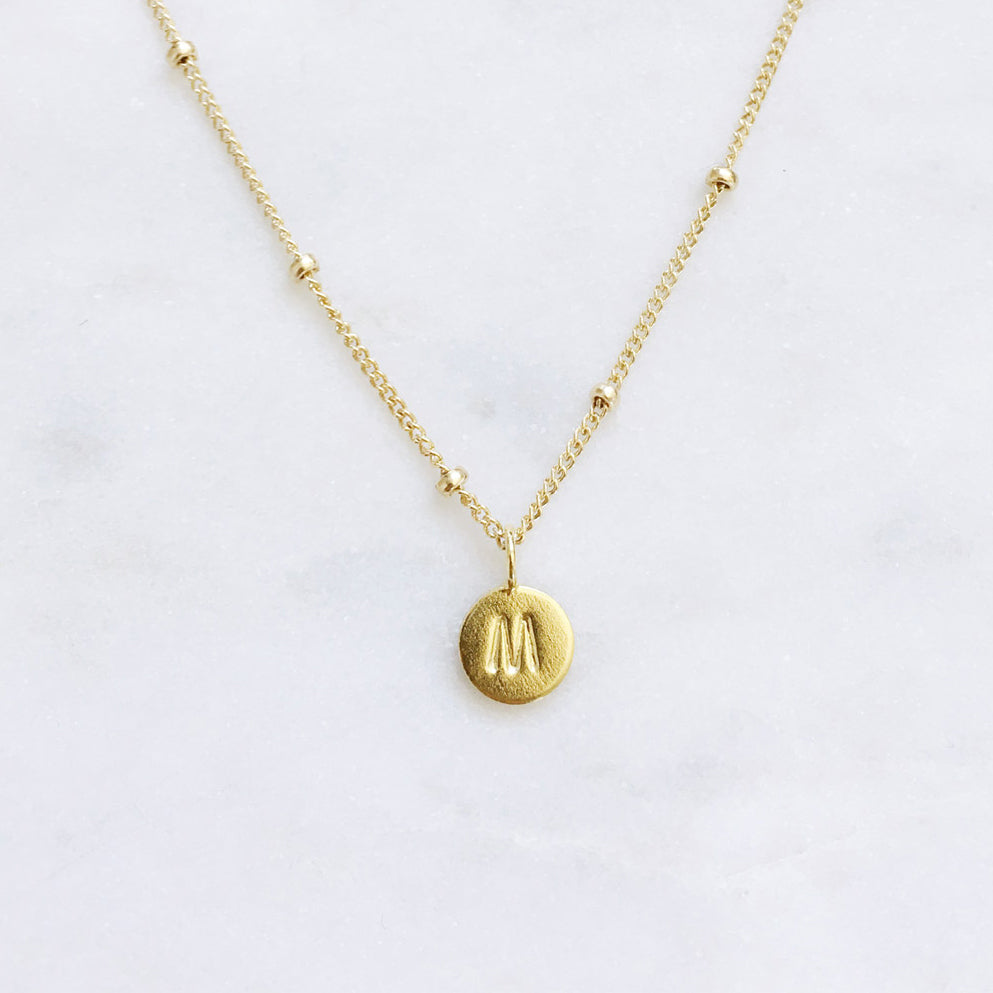 Dainty gold initial necklace with a letter M pendant on a 14k gold filled chain, handmade in Australia