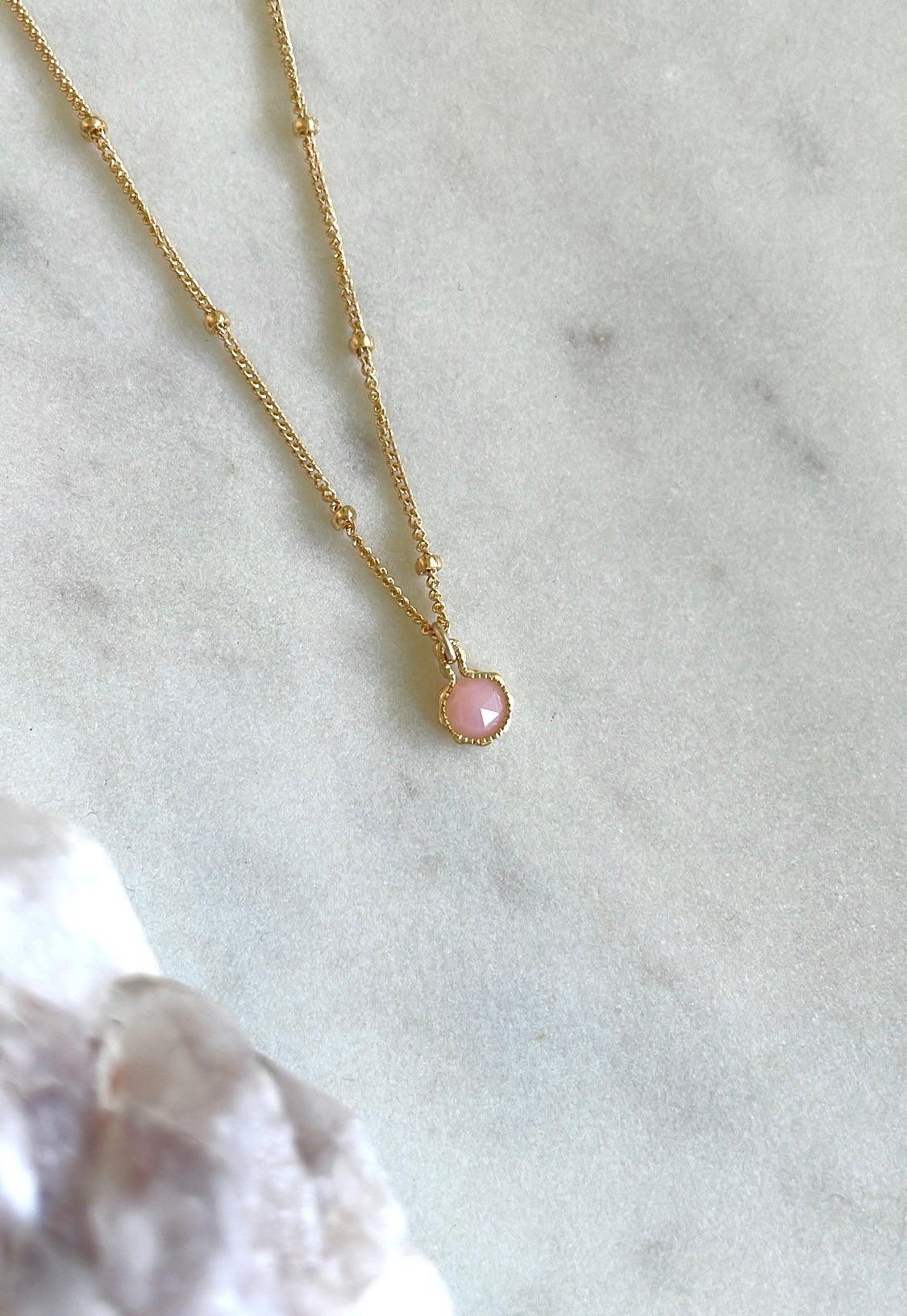 October birthstone necklace with genuine pink opal charm pendant on marble