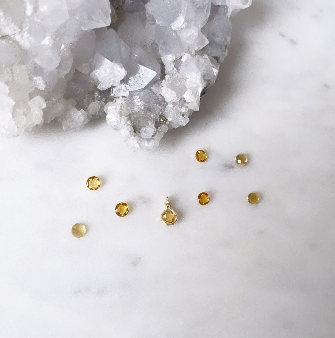 A round gold faceted rose cut citrine birthstone pendant charm surrounded by natural citrine gemstones