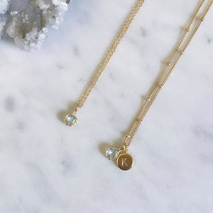 Gold Aquamarine necklace with initial pendant on marble