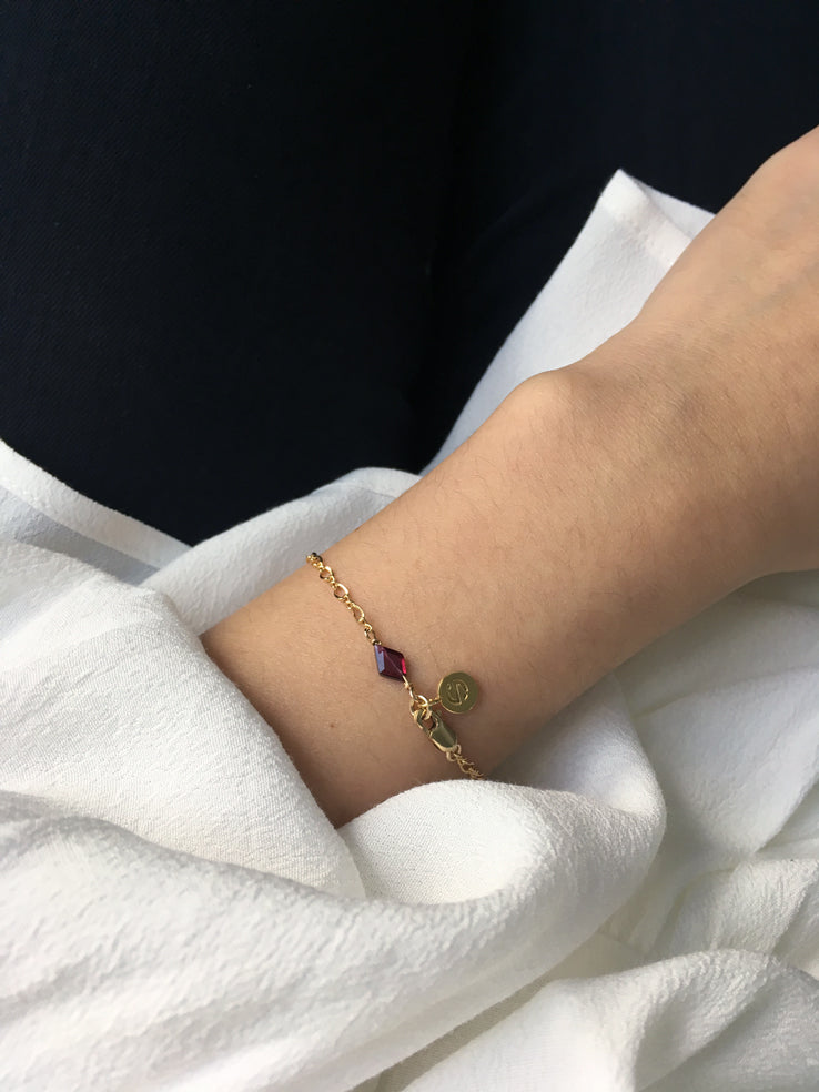 Dainty gold bracelet chain personalised with a diamond red garnet gemstone charm for January birthstone