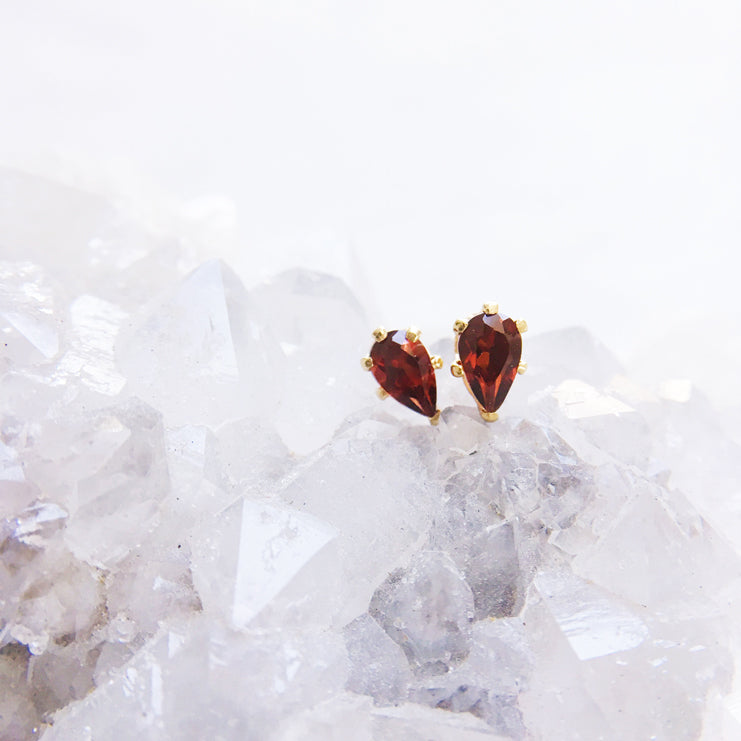 Teardrop gemstone gold stud earrings with red garnet gems