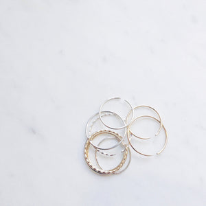 A group of plain, and twisted thin delicate ring bands in gold filled and sterling silver resting on a marble board