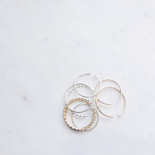 A scatter of gold filled and sterling silver minimalist rings on a marble board 
