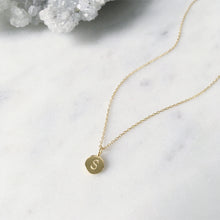 A gold letter "S" on an initial pendant hung on a dainty gold cable chain