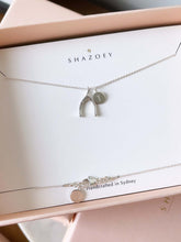 A silver wishbone necklace with a letter initial pendant
