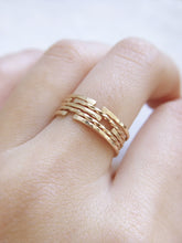 5 dainty gold ring bands with classic, hammered and twisted finishes, worn stacked on a finger