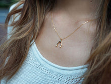 Woman with brown hair wearing a dainty gold wishbone necklace