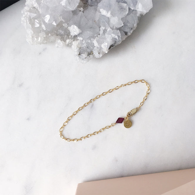 Fine gold bracelet chain with a red garnet gemstone birthstone charm