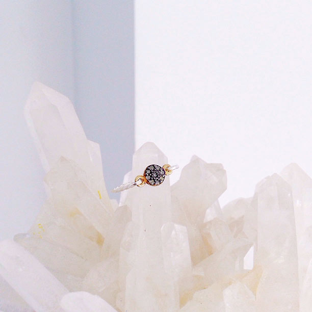 A dainty diamond ring in a gold setting with a minimalist sterling silver band 