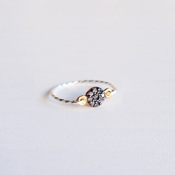 A modern ring with tiny rough diamonds set in a round circle with a silver twist band