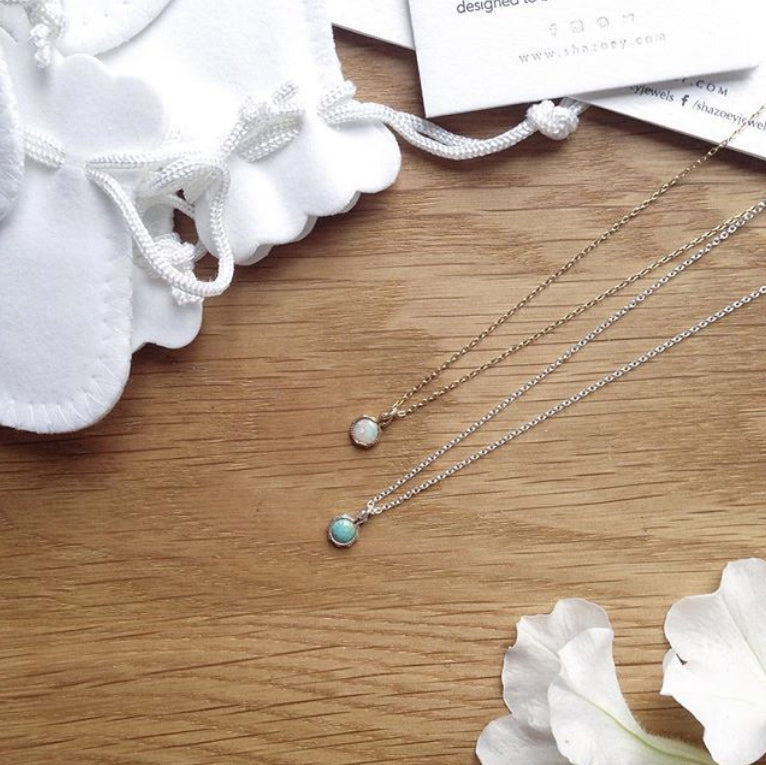 Gold opal necklace and sterling silver turquoise necklace on timber table