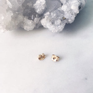 Gold earring backs next to crystal quartz