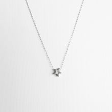 A tiny handmade sterling silver star necklace on a delicate silver chain