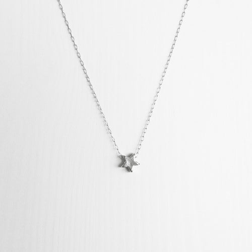 A tiny handmade sterling silver star necklace on a delicate silver chain
