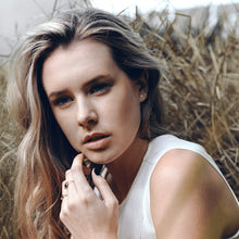 Model wearing dainty earring studs and gemstone rings