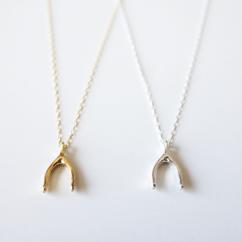 Minimalist fine gold and silver wishbone necklaces placed side by side