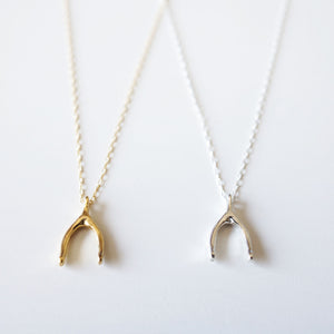 Minimalist fine gold and silver wishbone necklaces placed side by side